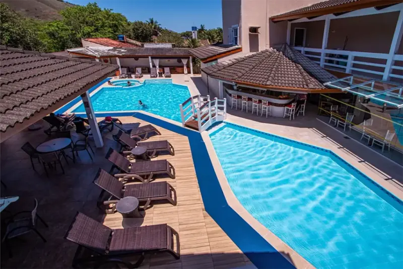 Piscinas do Ciribaí Praia Hotel cercadas por espreguiçadeiras em dia de sol